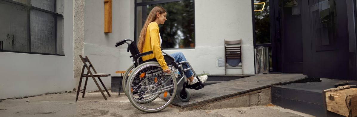 femme handicapée qui monte une rampe pour accéder à son domicile